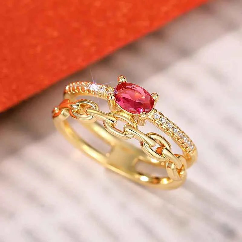 Oval cut gemstone ring - red stone in gold-tone band with pave zircon accents