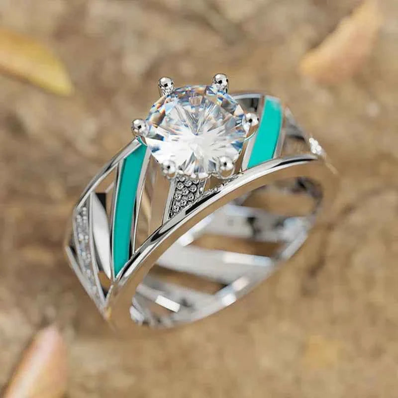 Silver engagement ring with round crystal prong setting and turquoise inlays on geometric band