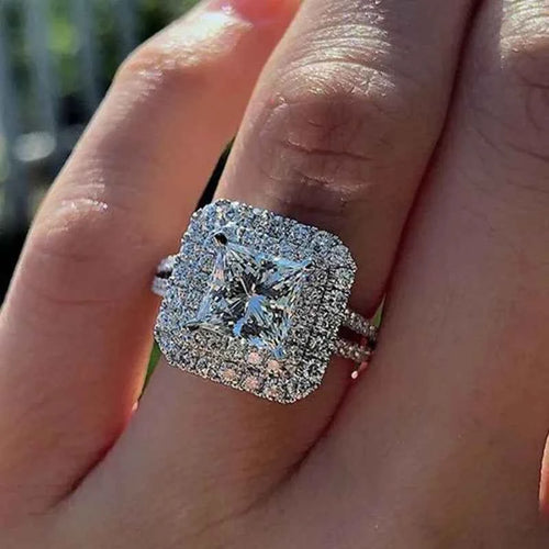 Princess cut diamond ring - square halo setting with brilliant center stone on white background
