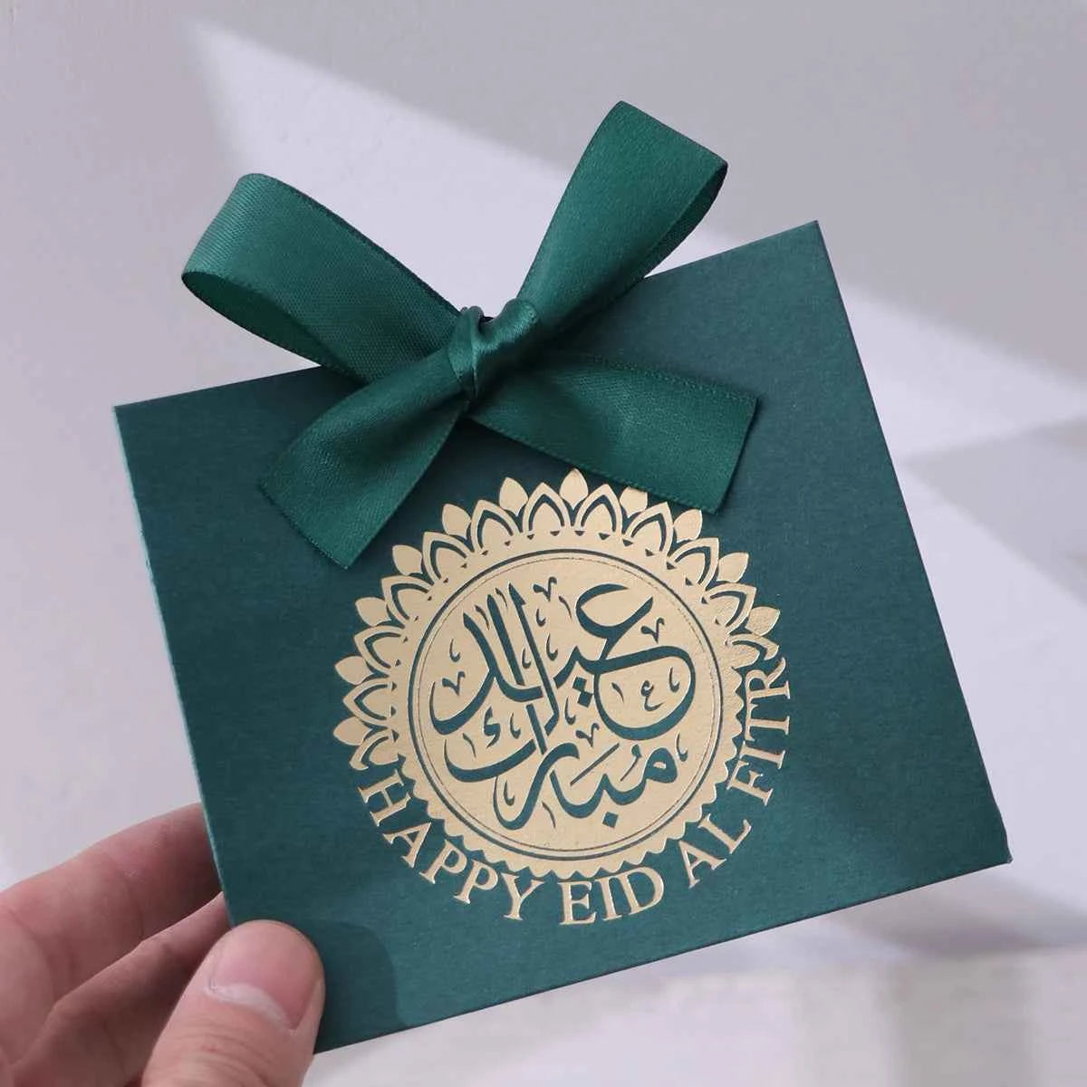 5 Exquisite and Compact Eid Gift Boxes, Each Featuring Elegant Black, Luxurious Green, and Pure White as Their Main Colors, Adorned with Delicate Arabic Script and Golden Circles, and Tied with Luxurious Gold and Silver Ribbo